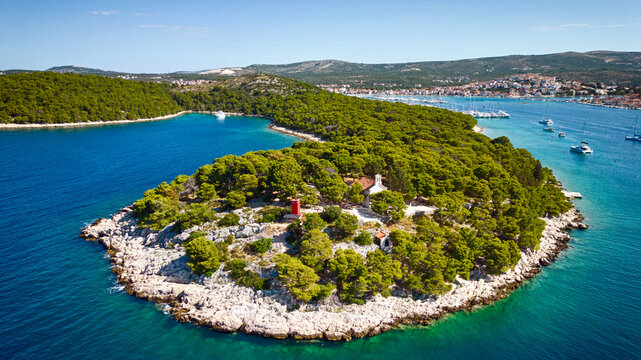 Aerial view of a verdant islet contrasts against the vivid turquoise sea, dotted with boats near the mainland, Rogoznica, &Aring;&nbsp;ibensko-kninska &Aring;&frac34;upanija, Croatia.