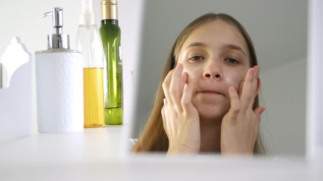 Teenager Girl Applying Lotion in Mirror, Blonde Young Use Moisturizer in Bathroom, Child, Kid use Face Cream, Beauty Cosmetics