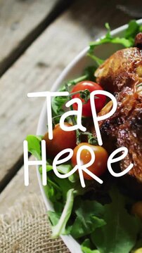 Tap Here text animation over roasted chicken with vegetables on wooden table