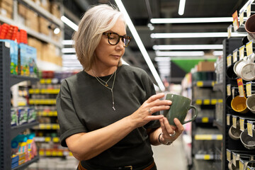 Woman shopping in a hypermarket exploring dinnerware and home decor while experiencing genuine...