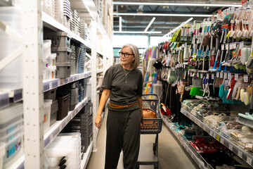 Mature woman shopping in a large home improvement store exploring diverse product categories and...