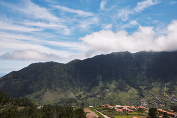 Panoramic view of a lush green mountain range with terraced agricultural slopes and a charming...
