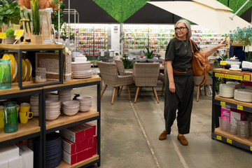 Mature woman shopping for home goods in a large home improvement store, exploring various product...