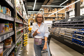 Middle-aged woman shopping in a home improvement store engaged with various department displays