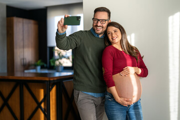 Overjoyed pregnant wife hugging husband enjoying romantic moments at home during the last trimester.