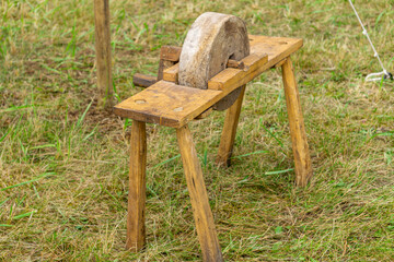 Manual sharpening stone on a wooden stand, used in historical reenactments.