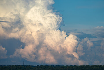 Dramatic cumulonimbus clouds creating a breathtaking spectacle in the sky above a distant forest,...