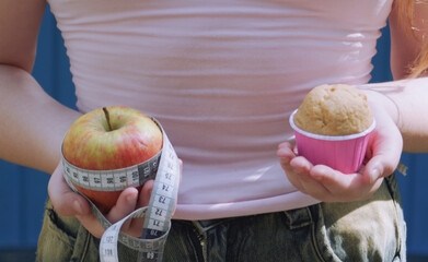 a girl holding an apple in one hand and a cake in the other, a weight loss concept
