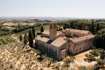 Sant'antimo abbey in tuscany, italy, surrounded by vineyards and olive groves, dominating the landscape