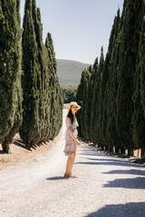 Tourist walking on a gravel road between cypress trees in tuscany, italy