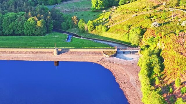 Aerial: Strines Reservoir, water storage reservoir, with forest during the day near Sheffield, South Yorkshire, England, pull out drone shot