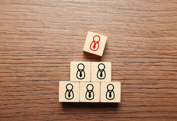 Dismissal. Cube with red human icon among others with black ones on wooden background, top view