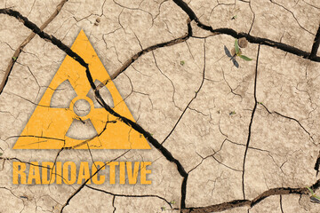 Orange radioactive sign on cracked dry earth, top view. Radiological pollution