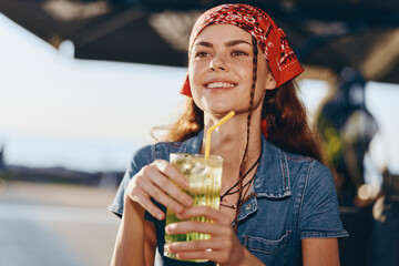 Lifestyle woman with modern boho-western denim street style drinking lemonade outdoors in warm...