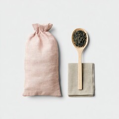 A pale pink linen pouch sits beside a wooden spoon filled with dark tea leaves, resting on a small linen napkin, all on a white background
