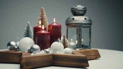 Elegant Christmas Still Life with Red Candles Silver Ornaments and Wooden Star on White Table in Soft Lighting Against a Grey Background - Powered by Adobe