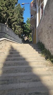 Tilt-up footage showing old concrete stairs and traditional buildings in the Abou Samra Neighborhood of Tripoli, Lebanon. Urban scene with historic architecture and local character.