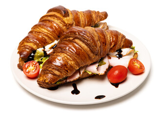 Two freshly baked classic delicious fresh organic croissants with ham, cheese, pesto sauce and tomatoes on a white ceramic plate isolated on white background