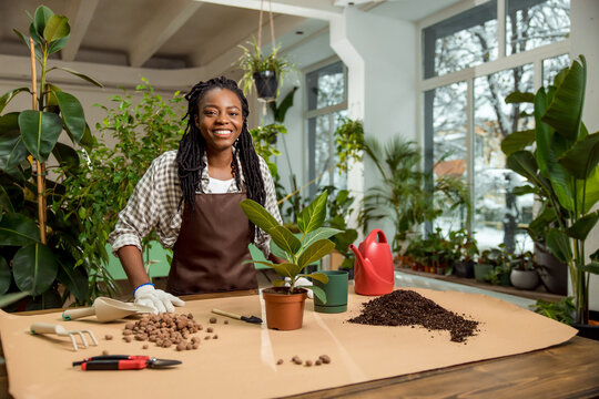 Smiling african american florist planting flowers and looking happy