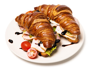 Two freshly baked classic delicious fresh organic croissants with ham, cheese, pesto sauce and tomatoes on a white ceramic plate isolated on white background