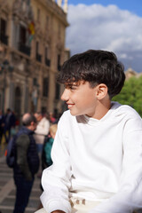 Happy Teenage Boy on Vacation in a City with People Strolling By
