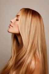 Fototapeta premium profile portrait of young woman with long blonde hair on beige background