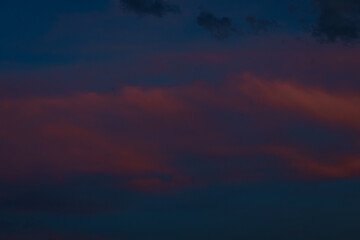 Dark clouds drift across a twilight sky painted in shades of deep blue and soft pink, creating a moody, atmospheric scene with ample space for text.