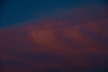 Dark clouds drift across a twilight sky painted in shades of deep blue and soft pink, creating a moody, atmospheric scene with ample space for text.