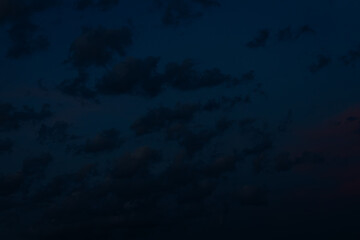 A large, dark cloud floats in a deep twilight sky, tinted with faint pink light, creating a minimalist, moody scene with ample space for text.