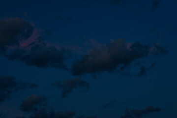 A large, dark cloud floats in a deep twilight sky, tinted with faint pink light, creating a minimalist, moody scene with ample space for text.