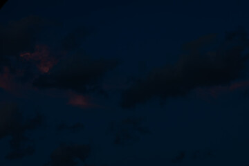 A large, dark cloud floats in a deep twilight sky, tinted with faint pink light, creating a minimalist, moody scene with ample space for text.