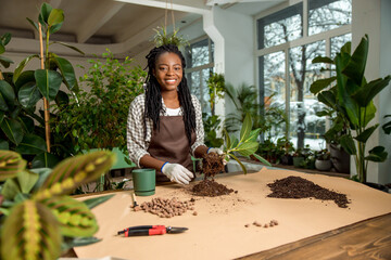 Smiling flower shop assistant planting flowers and feeling good