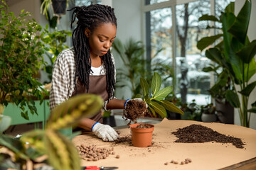 Florist putting soil into the flower pot while planting the flowers