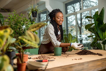 Florist putting soil into the flower pot while planting the flowers