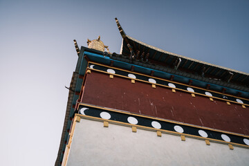 ornate roof details of a Tibetan Buddhist temple in Shangri-La, China, featuring golden dragon...