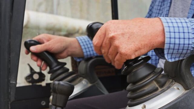 Person Hand Operating The Controls Of Excavator Working In The Farm. - closeup shot