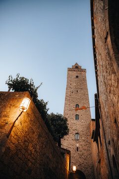 Fototapeta Torre del diavolo towering over san gimignano alley at dusk in tuscany