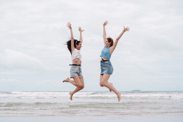 Obraz premium Two young women jumping with joy on the beach friendship, freedom, happiness, and summer fun. vacation, lifestyle, youthful energy, and beach holiday.