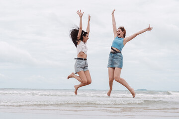 Obraz premium Two young women jumping with joy on the beach friendship, freedom, happiness, and summer fun. vacation, lifestyle, youthful energy, and beach holiday.