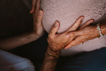 Fototapeta premium Hands Gently Cradling a Pregnant Belly in Warm Embrace