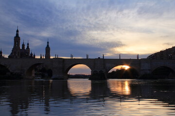Obraz premium Cathedral-Basilica of Our Lady of the Pillar and Puente de Piedra reflecting in the Ebro river in the sunset, Zaragoza, Spain