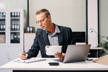 Fototapeta premium Business man working at office with laptop and documents on desk, financial adviser analyzing data.