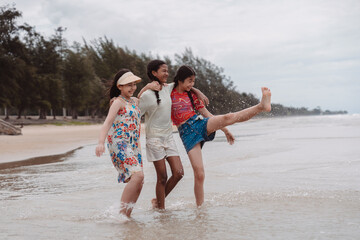 Asian and multicultural friends walking and splashing in beach water, enjoying childhood freedom, friendship, and outdoor fun in a playful and joyful summer moment.