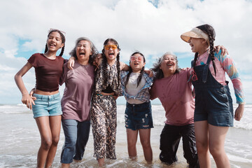 Happy Asian family group, senior women and kids enjoying playful beach. Celebrating love, wellness, and multi generational togetherness by the sea.