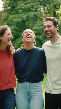 A Group of Diverse Young Friends Walking with Arms Around Each Other and Laughing Heartily in a Park, Ideal for Videos about Friendship, Joy, and Togetherness