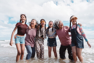 Happy Asian family group, senior women and kids enjoying playful beach. Celebrating love, wellness, and multi generational togetherness by the sea.
