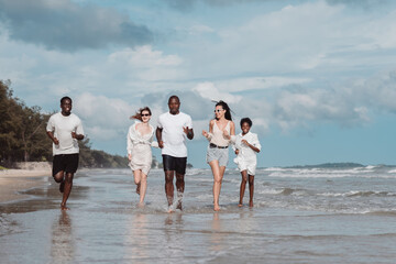 Diverse group of friends running together on the beach. Active friendship, summer fun, freedom, and energetic lifestyle by the sea.