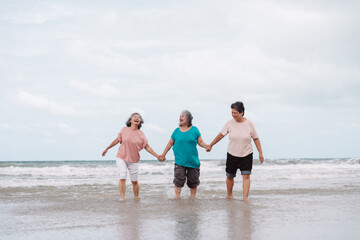 Asian senior females walking on the beach, smiling and enjoying retirement freedom. insurance, life...