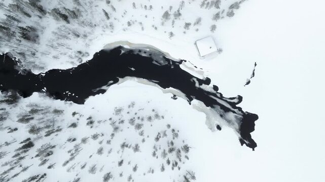 Top-down aerial shot of a river flowing through a snowy forest