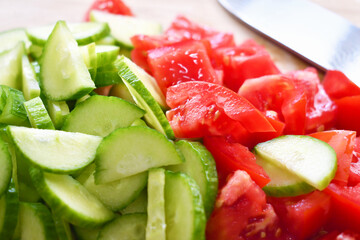 Cucumber and tomato slices on chopping board. Healthy food. Summer fresh vegetables.